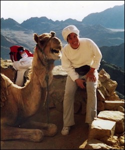 Woman leaning toward camel smiling